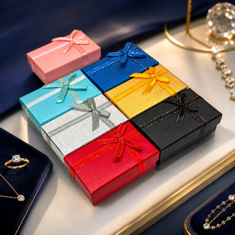 Seven colorful B2632 bow jewelry gift boxes displayed with fine jewelry on a navy and champagne boutique counter