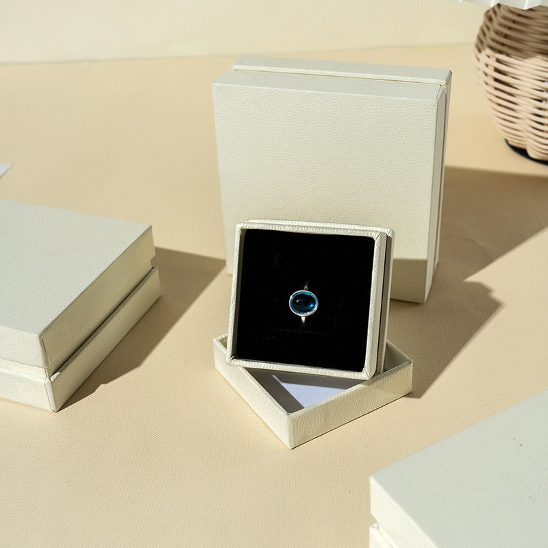 Open off-white lid-and-base jewelry box with black insert for ring presentation