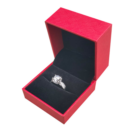 Open red ring box with black velvet interior holding a diamond ring
