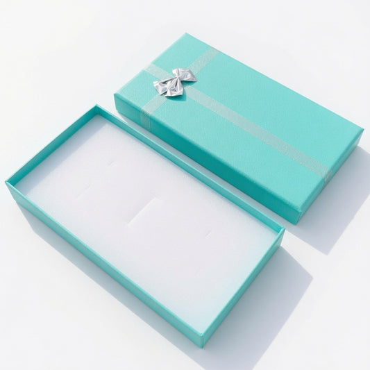 Open lake blue paper necklace box with silver ribbon bow and white insert