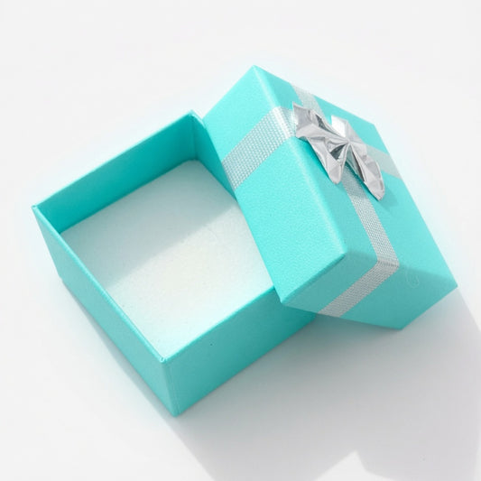 Open lake blue paper ring box with silver ribbon bow and white insert