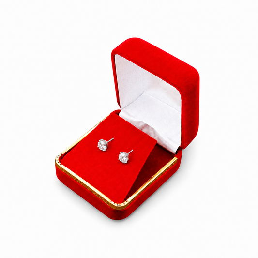 Red velvet earring box with gold trim displaying two stud earrings