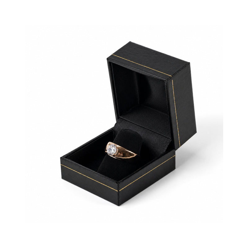 Black jewelry ring box with gold trim, open with a ring