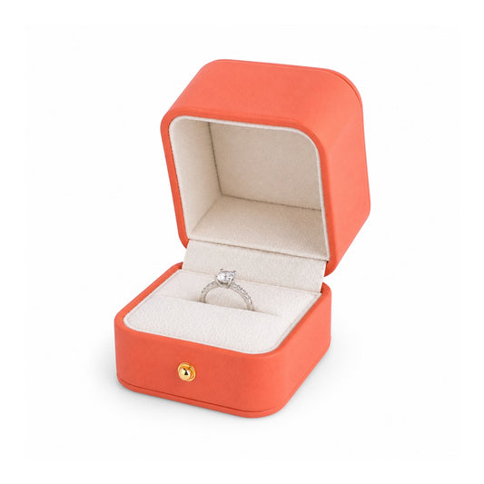 orange PU ring box open in a three-quarter view with a diamond ring.
